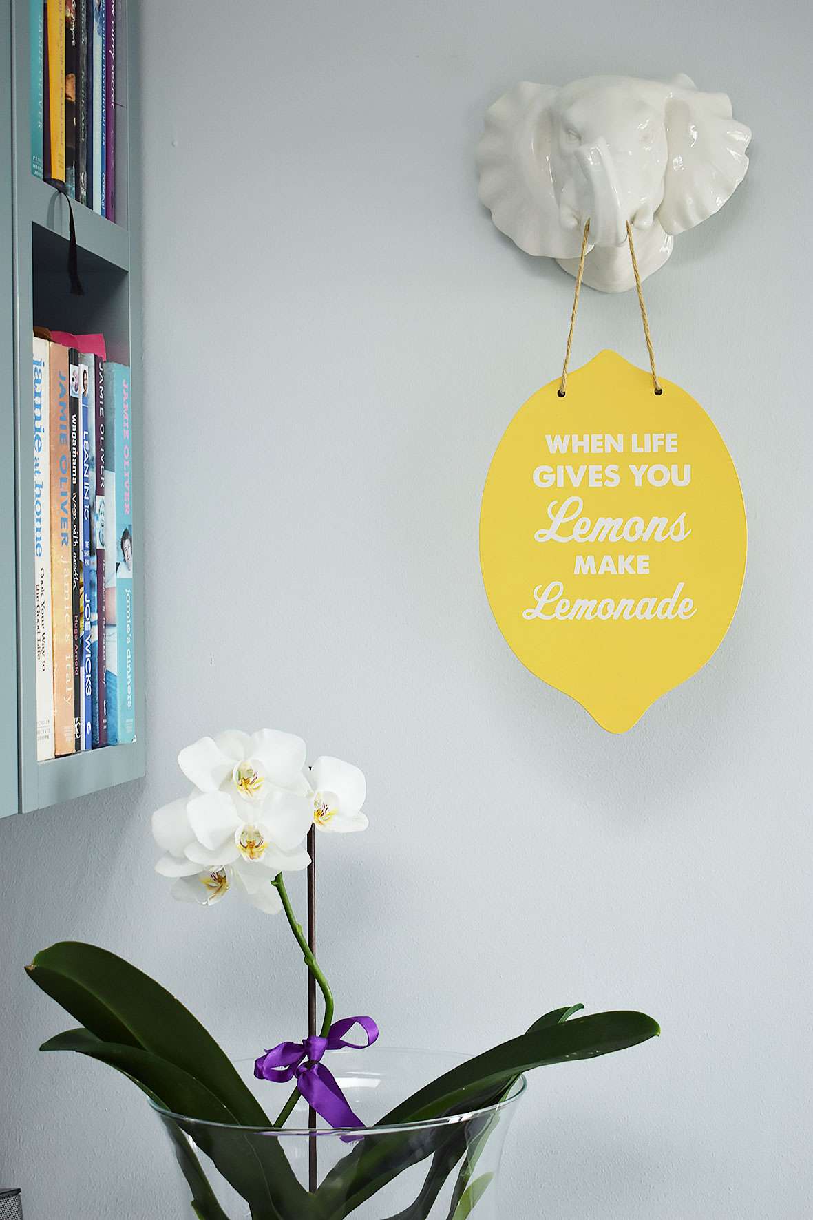 white orchid in vase below 'when life gives you lemons make lemonade' sign