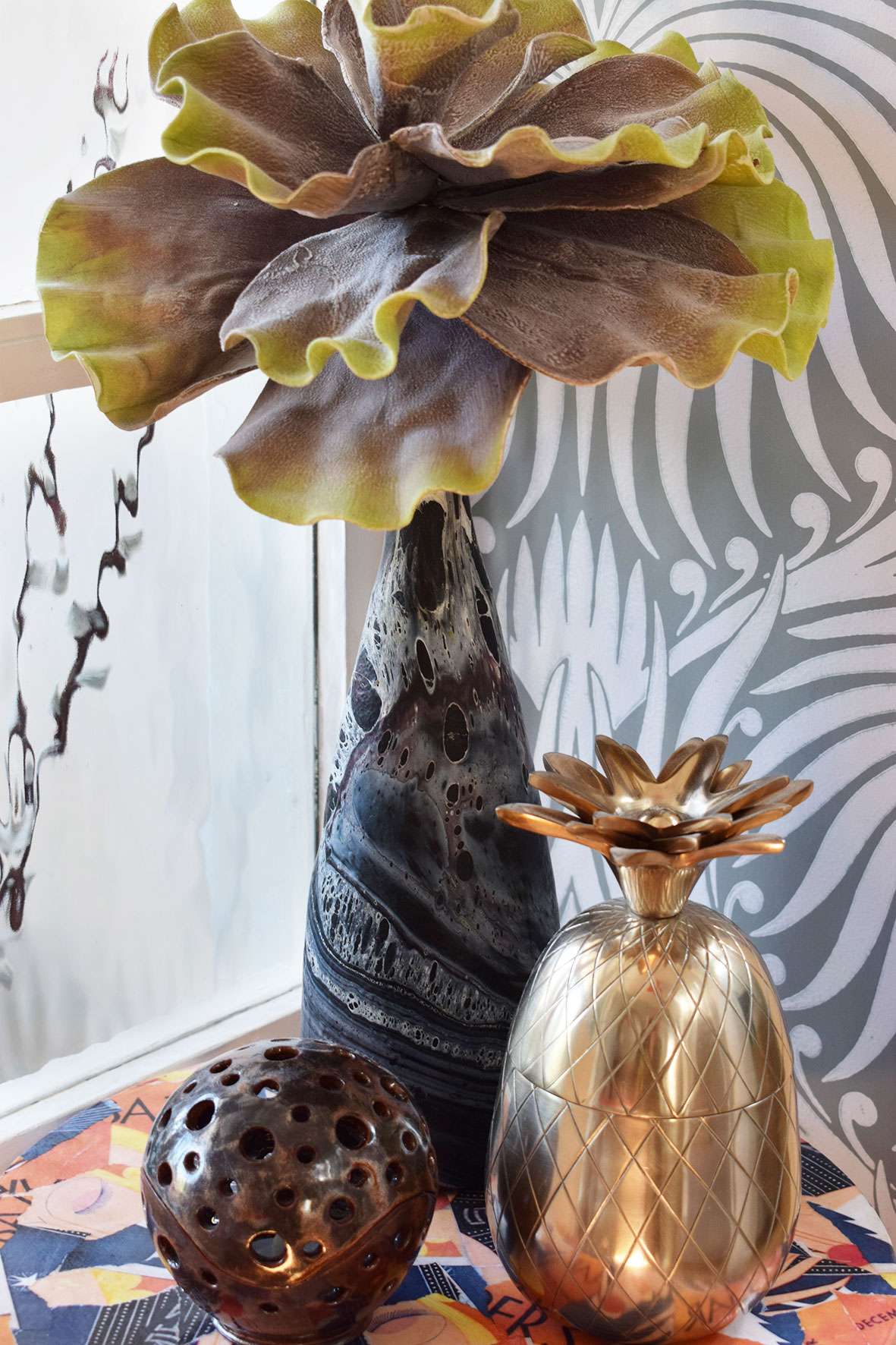 artificial plant stem in black marble vase and gold pineapple ornament on table