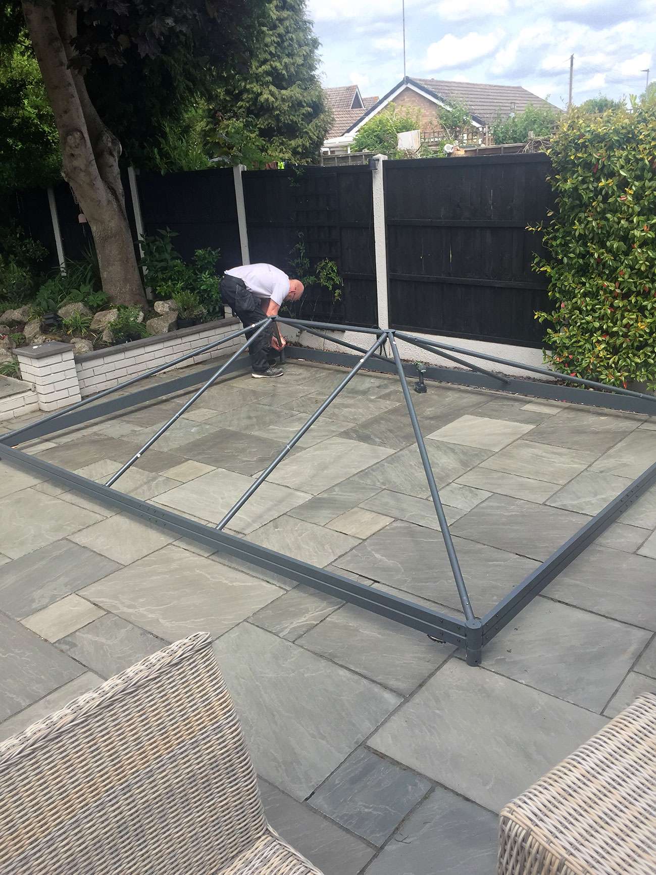 Gazebo ceiling frame being erected by man.