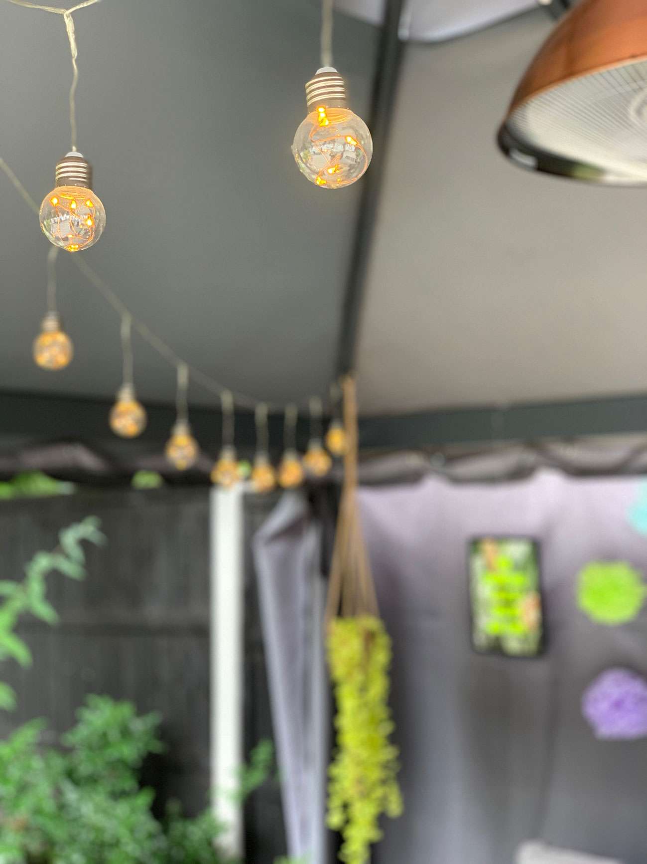 Festoon lights in a gazebo with hanging planter in background