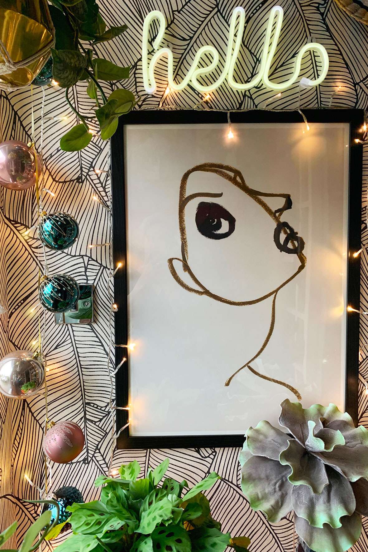 wall print with hello light above and pink and teal glass baubles hanging to the left