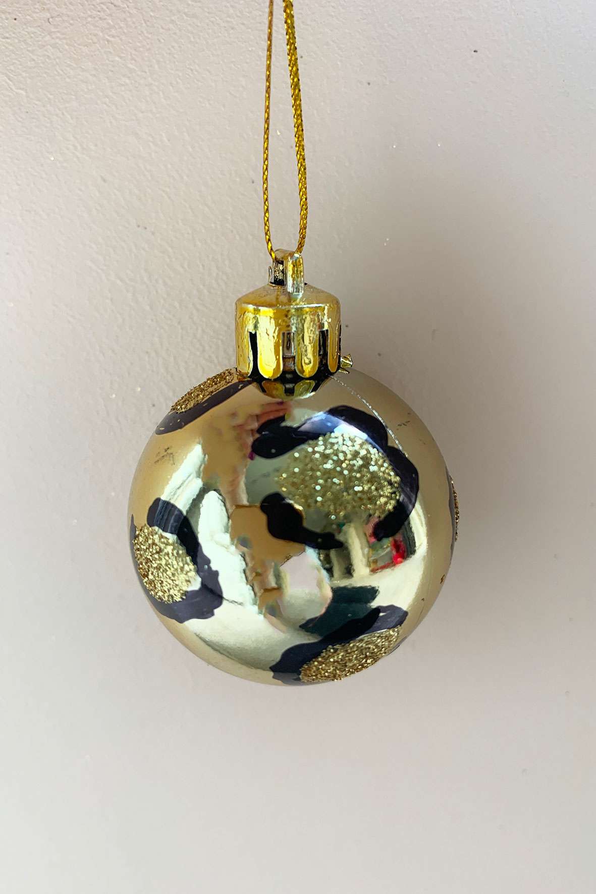 A shiny gold bauble with a glitter leopard print design