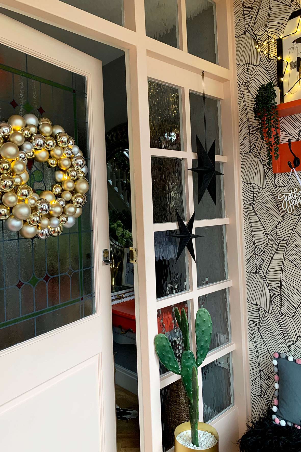entryway with gold bauble wreath on door and star hanging decorations