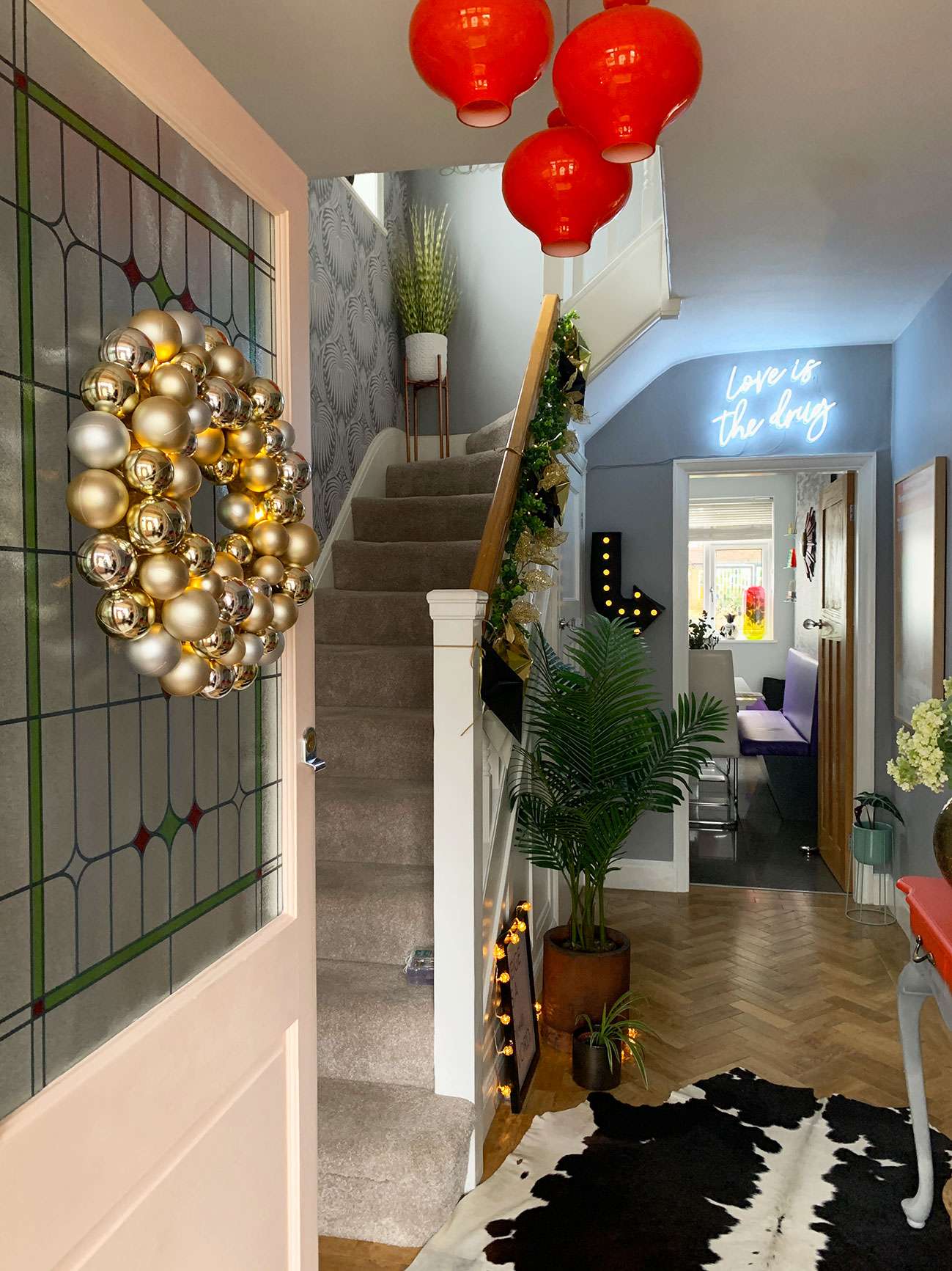 door with gold bauble wreath on leading into hallway with Christmas decorations