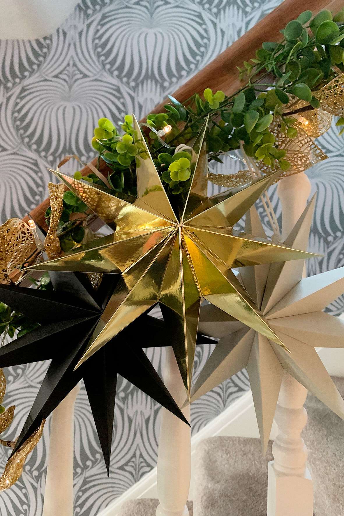 close up of gold, grey and black paper stars on stair rail garland