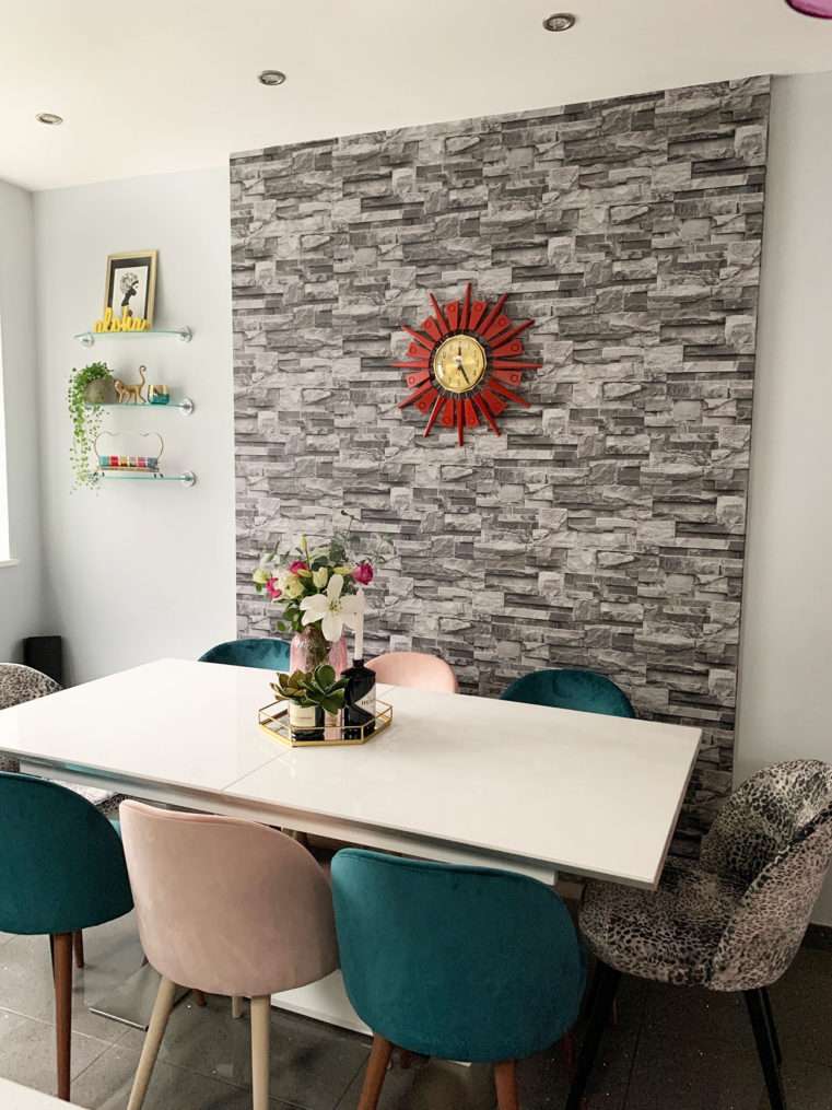 colourful dining area with velvet chairs and slate feature wall.