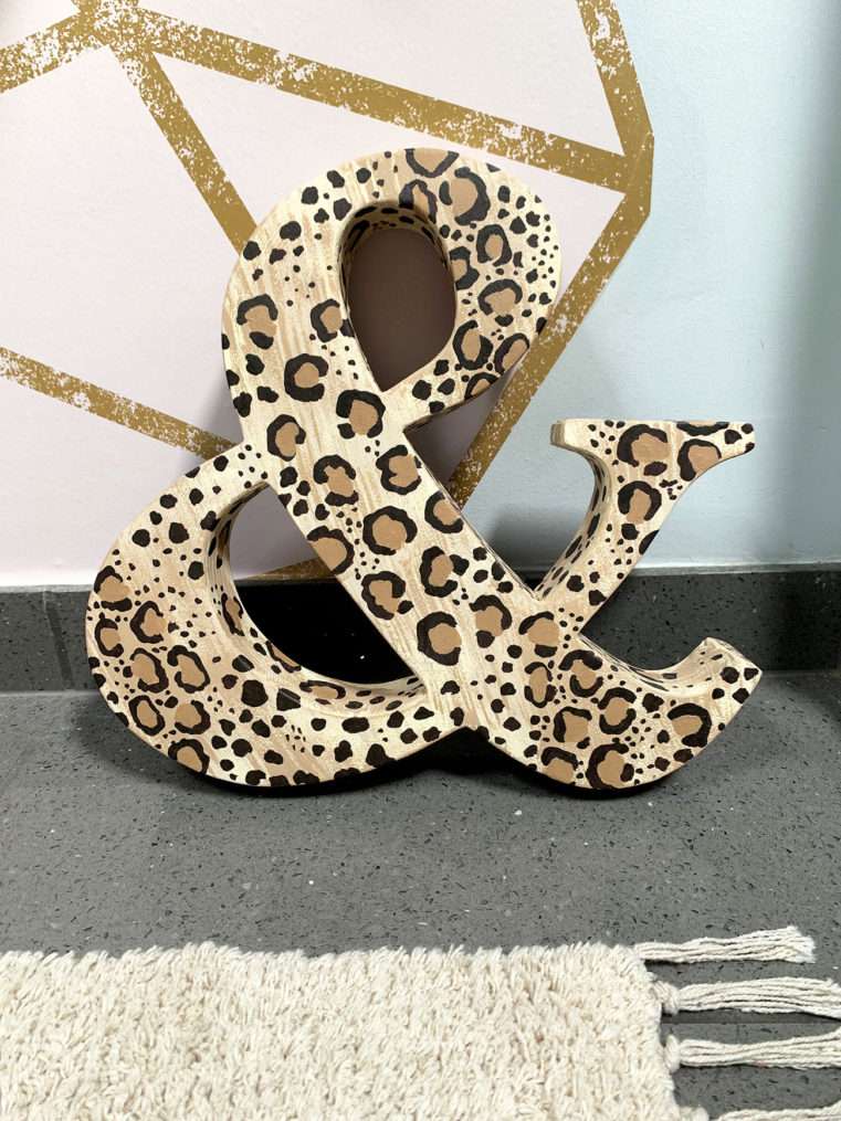 leopard print ampersand ornament leaning against wall.