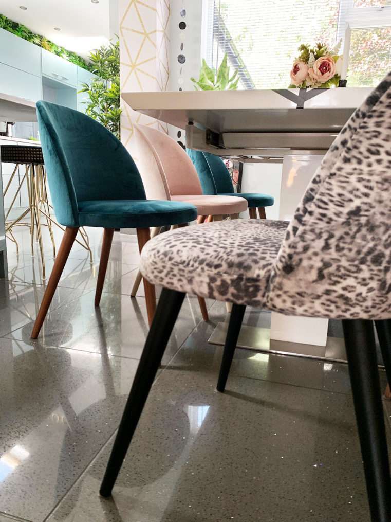 mixed velvet dining chairs in blush, teal, and leopard print.