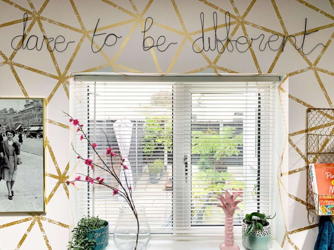 kitchen window with blush and gold geometric wallpaper decorated with 'dare to be different' typography wire words.