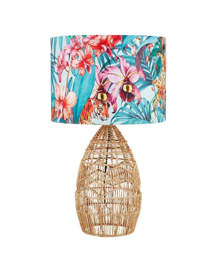 Tropical round lampshade on a rattan base in front of a white background.