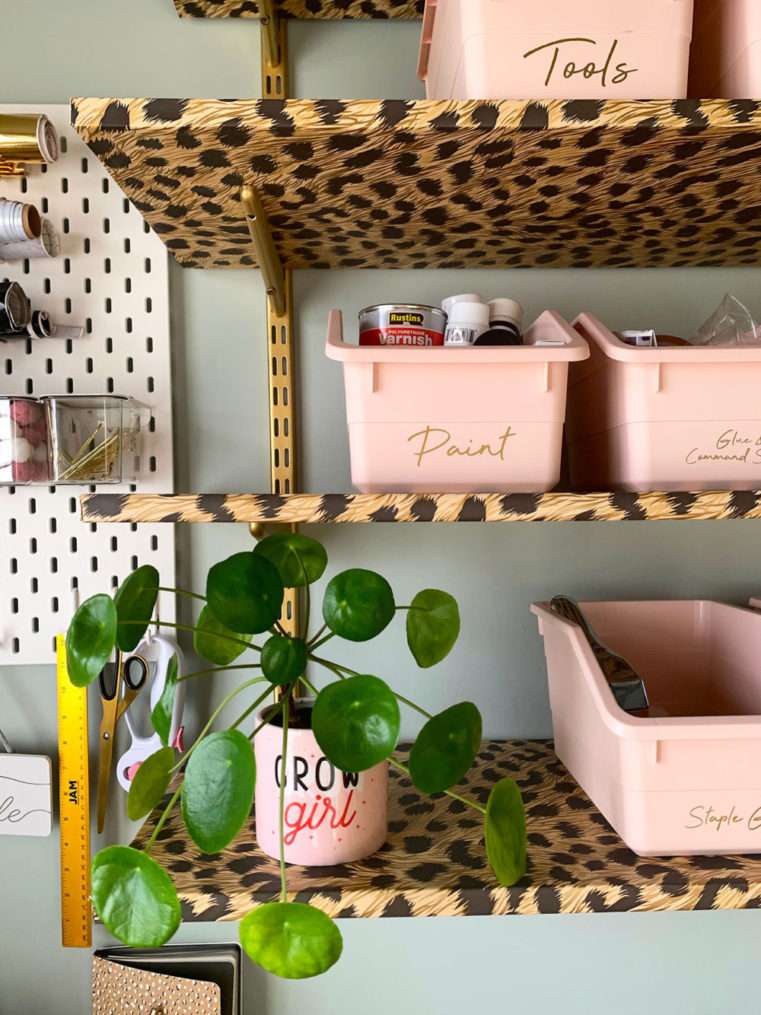 Close up of blush craft storage boxes and organisation on Leopard print and gold shelves with a soft green background.