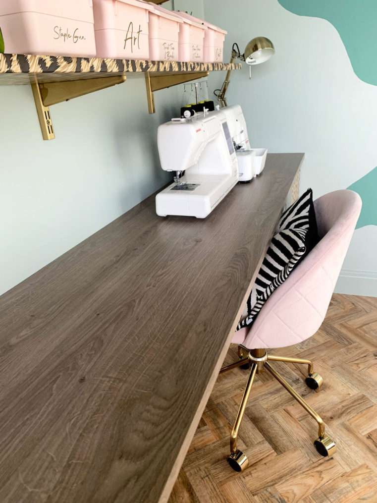 Wood effect worktop with sewing machine on top and shelf with craft items above.
