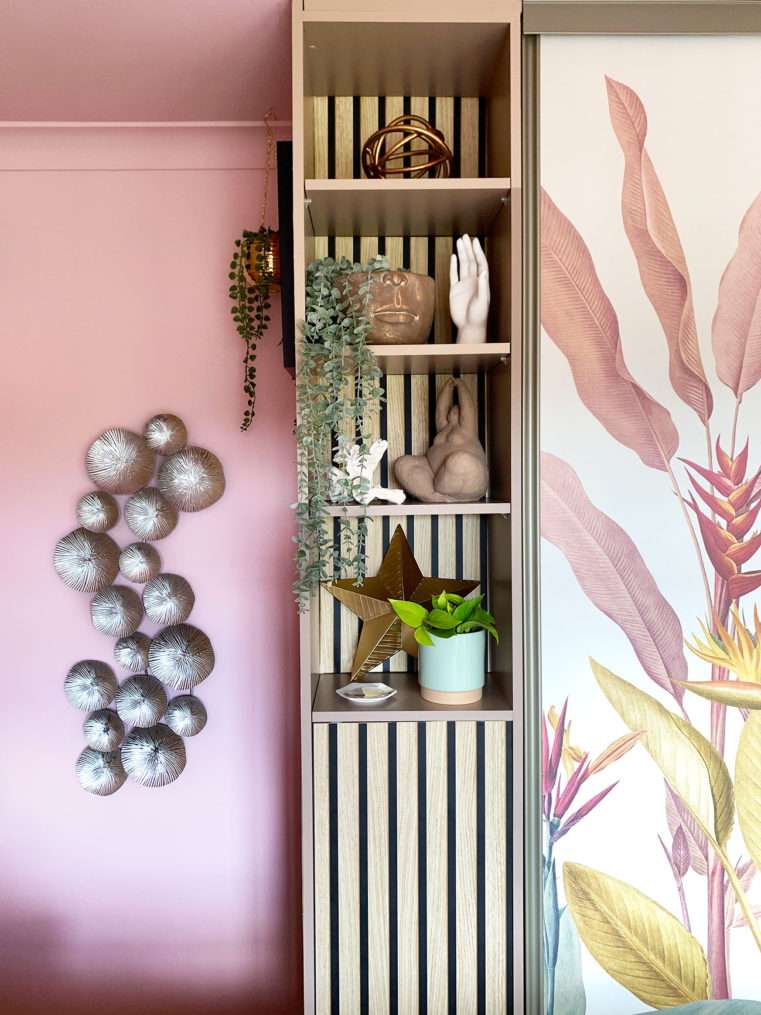 Bedroom shelf with wood slat back, quirky sculpture ornaments and pink relaxing decor.