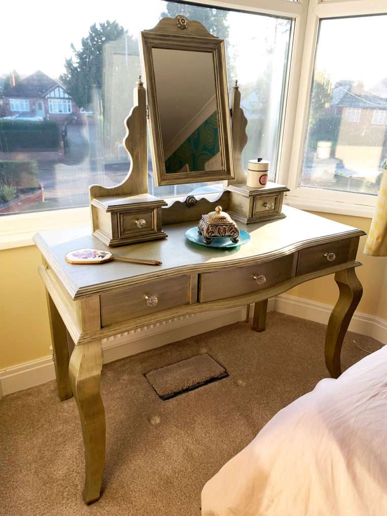 Bedroom window area before makeover with champagne dressing table with mirror.
