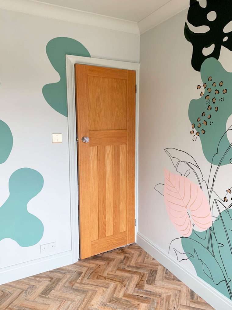 Before shot of oak door in green, blush, and leopard decorated wall mural.
