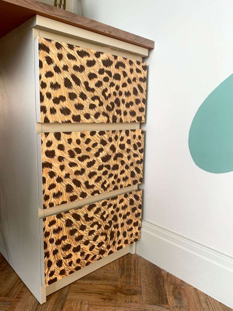 Close up of drawers covered in leopard print wallpaper.