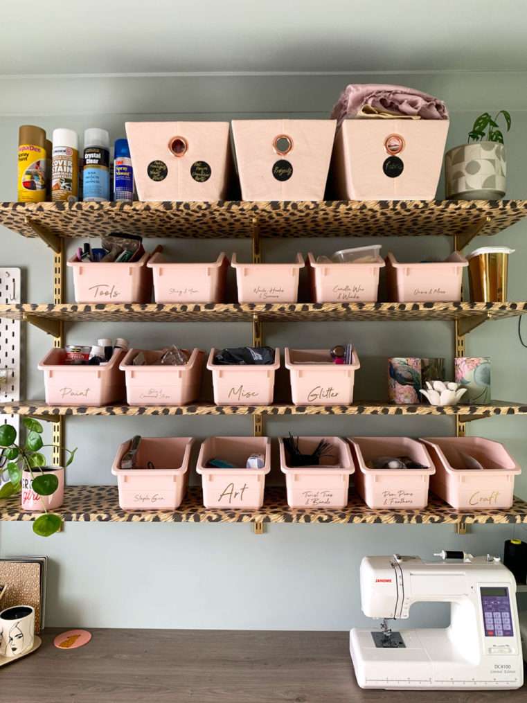 Blush craft storage boxes and organisation on Leopard print and gold shelves with a soft green background.