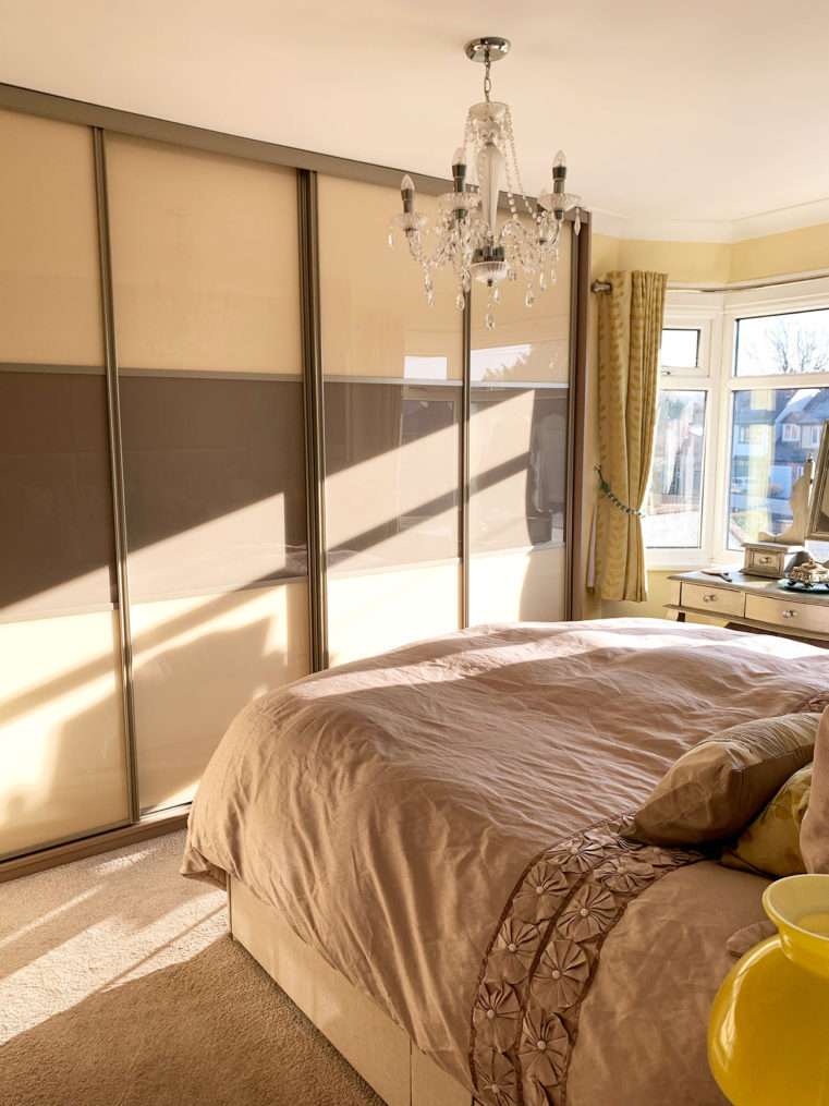 Beige glass sliding wardrobes and beige bedding before makeover.