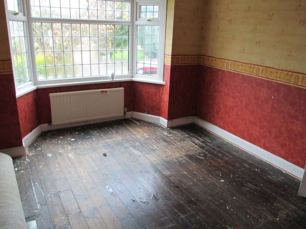 Estate agents shot of before bedroom before. yellow and rust wallpaper.