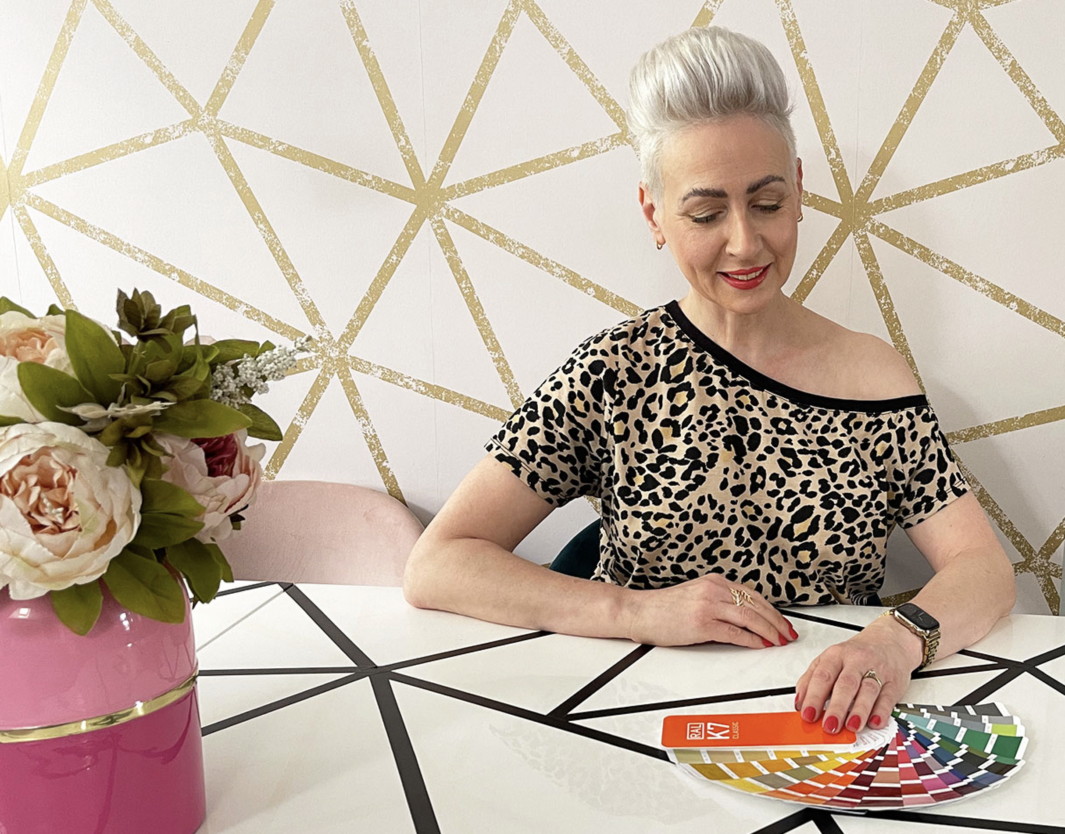 Woman at table kitchen looking at colour palette with pink decor and flowers